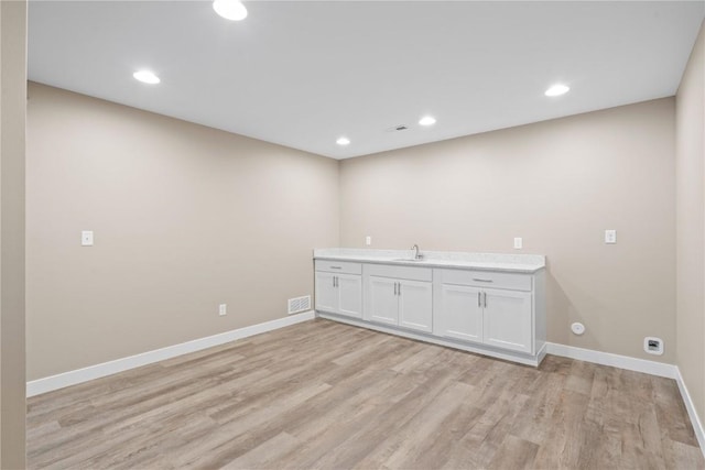 laundry room featuring visible vents, light wood-type flooring, baseboards, and a sink