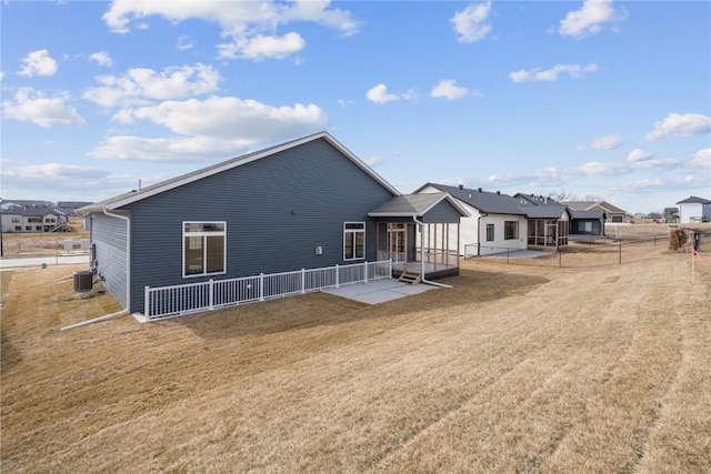 back of house with fence, central AC unit, and a lawn