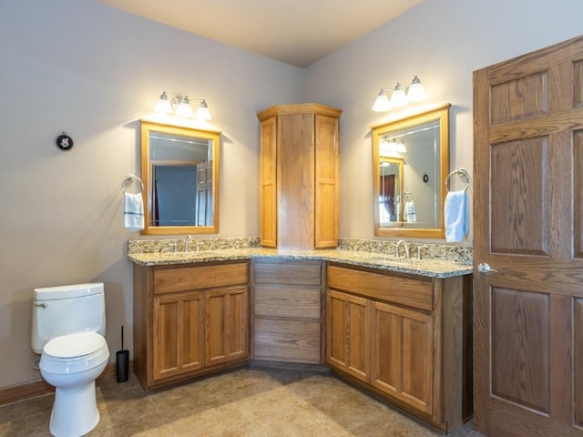 full bath with a sink, toilet, double vanity, and tile patterned floors