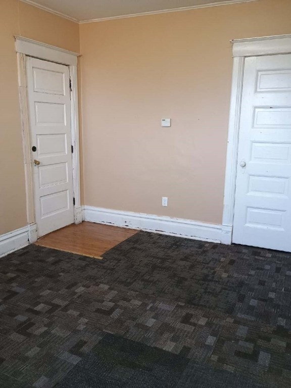 carpeted spare room featuring baseboards and crown molding