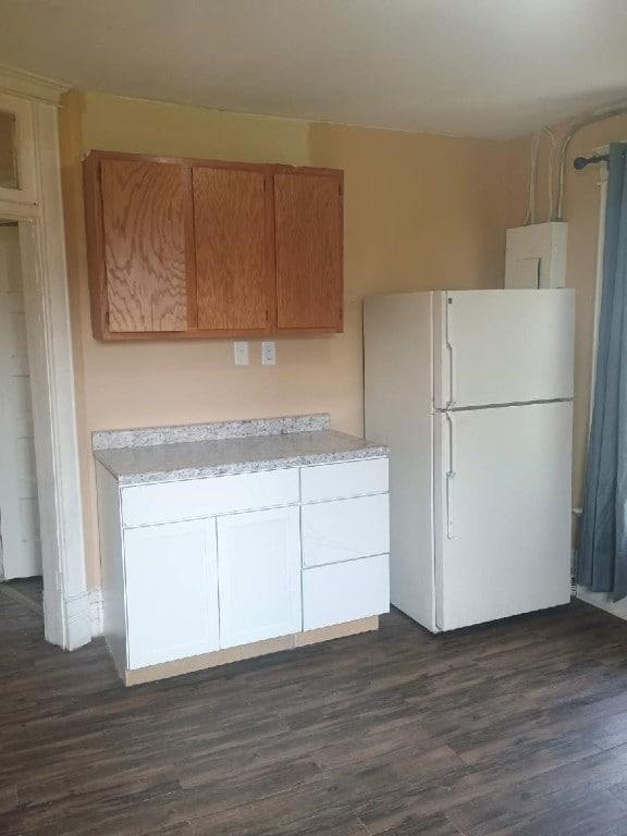 kitchen featuring freestanding refrigerator, dark wood-style flooring, light countertops, and electric panel