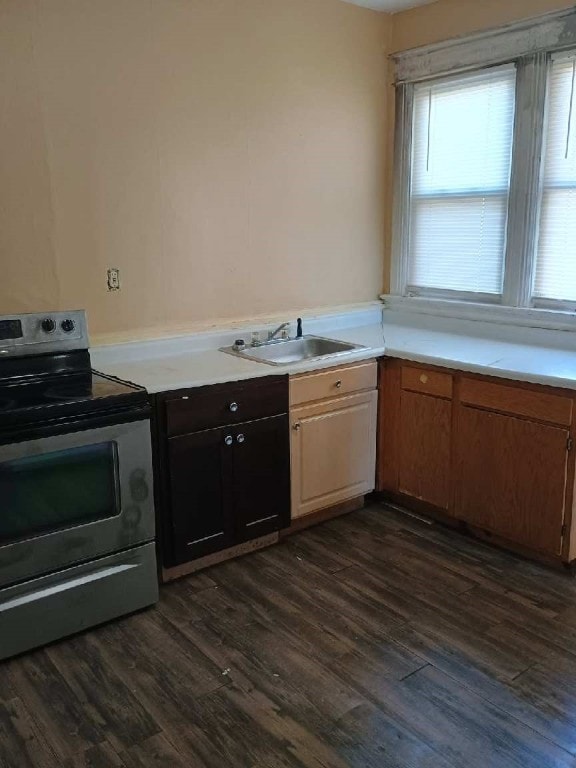 kitchen with a sink, stainless steel range with electric stovetop, light countertops, and dark wood finished floors