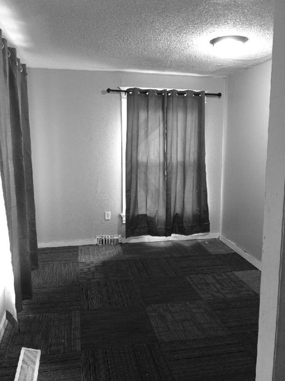 spare room with a textured ceiling and baseboards