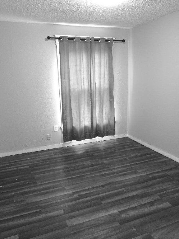 512/514 Mckinley St SE, Cedar Rapids, IA 52403 - spare room featuring a textured ceiling, dark wood-style floors, and baseboards