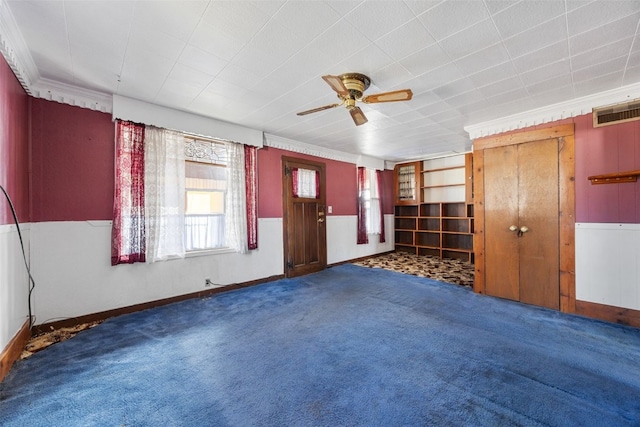 carpeted spare room featuring visible vents, a ceiling fan, and crown molding