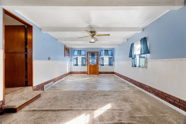 unfurnished room with beamed ceiling, wainscoting, visible vents, and carpet
