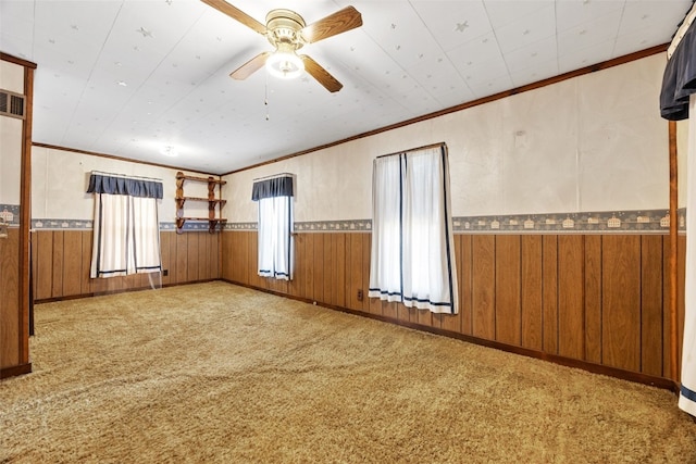 spare room featuring a wainscoted wall, wood walls, ceiling fan, and carpet floors