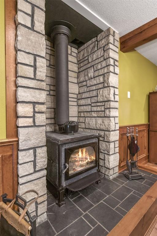 3098 Sandy Beach Rd NE, Solon, IA 52333 - details with beam ceiling, a textured ceiling, wainscoting, and a wood stove