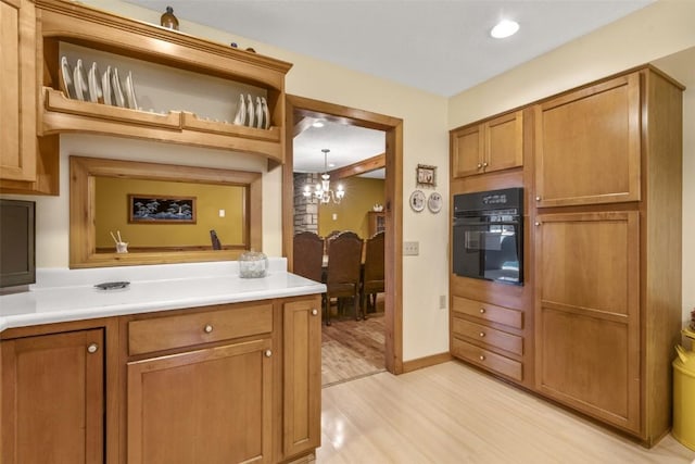 3098 Sandy Beach Rd NE, Solon, IA 52333 - kitchen with brown cabinets, a notable chandelier, light wood-style flooring, black oven, and light countertops