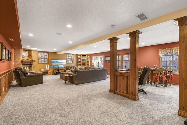 3098 Sandy Beach Rd NE, Solon, IA 52333 - living area with a wainscoted wall, a textured ceiling, a fireplace, light colored carpet, and ornate columns