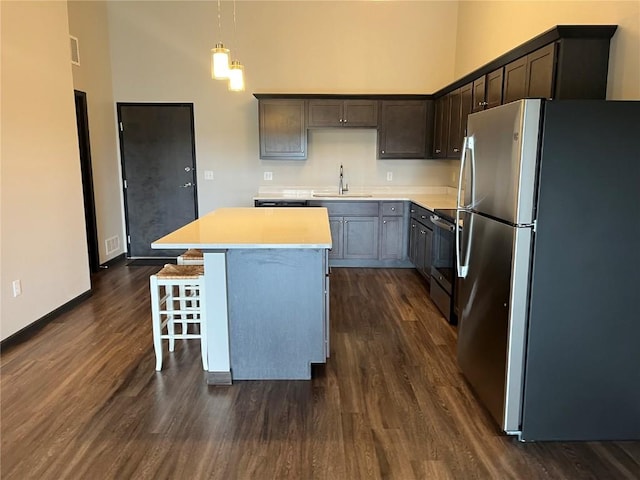kitchen with stainless steel appliances, a sink, a high ceiling, dark wood-type flooring, and a kitchen island