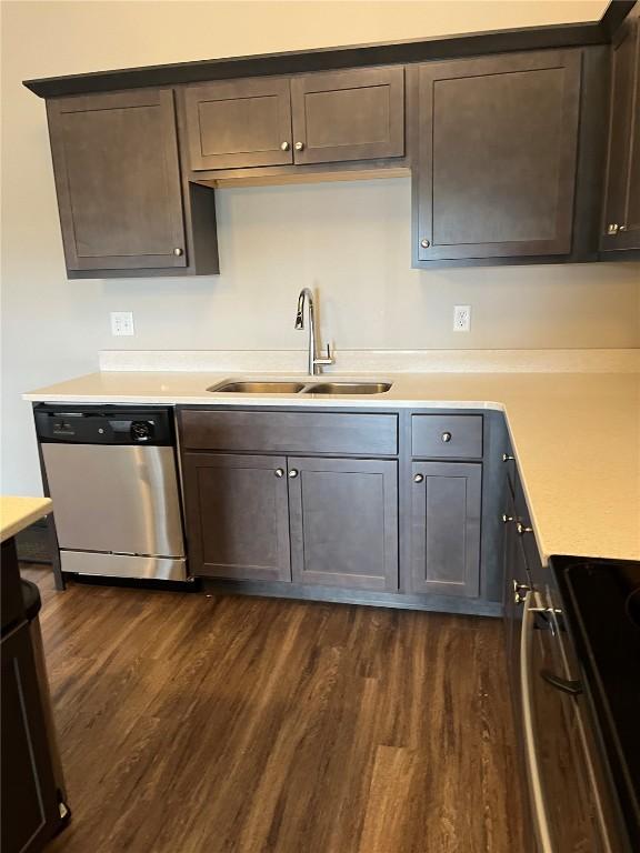 kitchen featuring stainless steel dishwasher, a sink, dark wood finished floors, light countertops, and dark brown cabinets