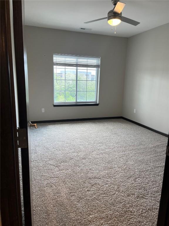 empty room featuring carpet floors, baseboards, and a ceiling fan