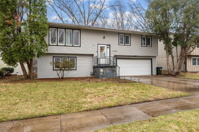 bi-level home featuring concrete driveway, a garage, and a front yard