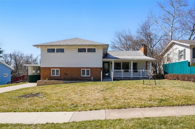 view of front of property featuring brick siding, a porch, a chimney, and a front yard