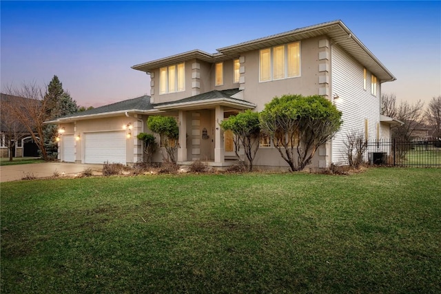 view of front facade featuring stucco siding, driveway, fence, an attached garage, and a front yard
