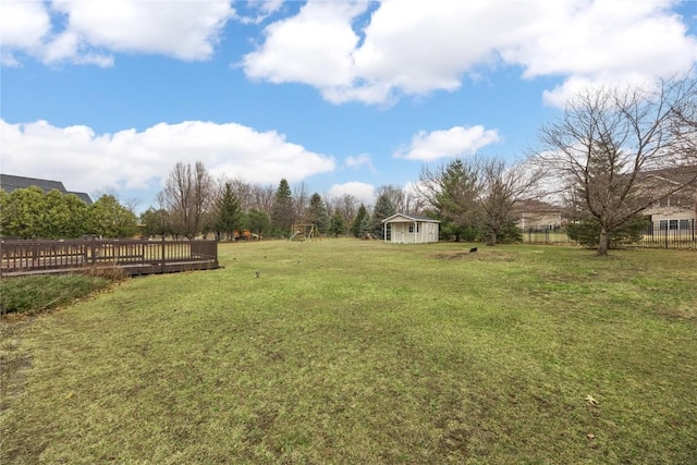 view of yard featuring a wooden deck, an outbuilding, and fence
