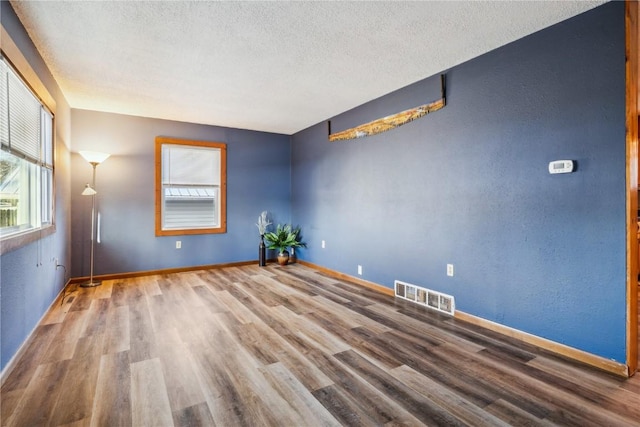206 E Jackson St, Grandview, IA 52752 - unfurnished room featuring baseboards, wood finished floors, visible vents, and a textured ceiling
