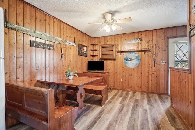 206 E Jackson St, Grandview, IA 52752 - dining space with wood finished floors, a ceiling fan, baseboards, wood walls, and a textured ceiling