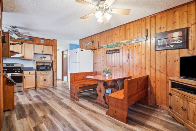 206 E Jackson St, Grandview, IA 52752 - dining area featuring wooden walls, a ceiling fan, light wood-style floors, and a textured ceiling