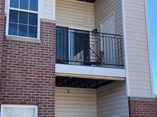 view of side of home featuring brick siding and a balcony