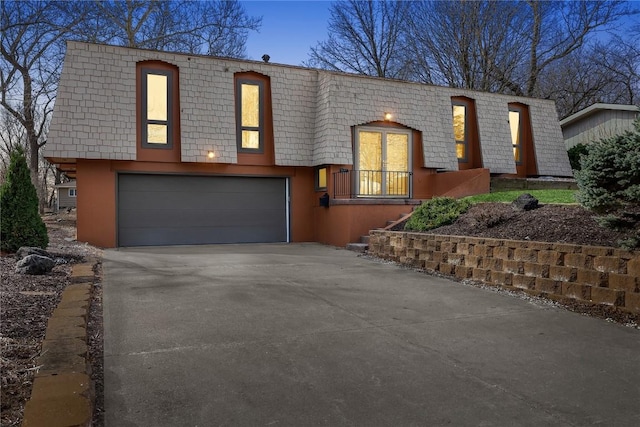 view of front of home with driveway and mansard roof