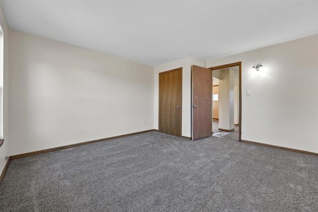 carpeted empty room featuring baseboards