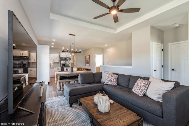 living area featuring recessed lighting, dark wood-style flooring, a tray ceiling, and a ceiling fan