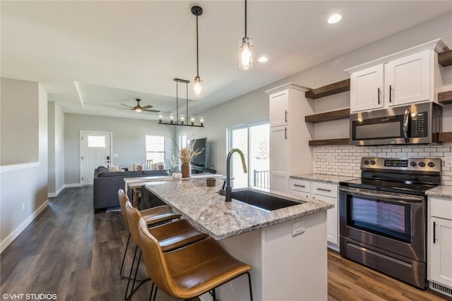kitchen with backsplash, open shelves, ceiling fan, stainless steel appliances, and a sink