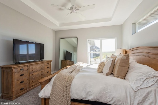 bedroom featuring multiple windows, ceiling fan, and a raised ceiling