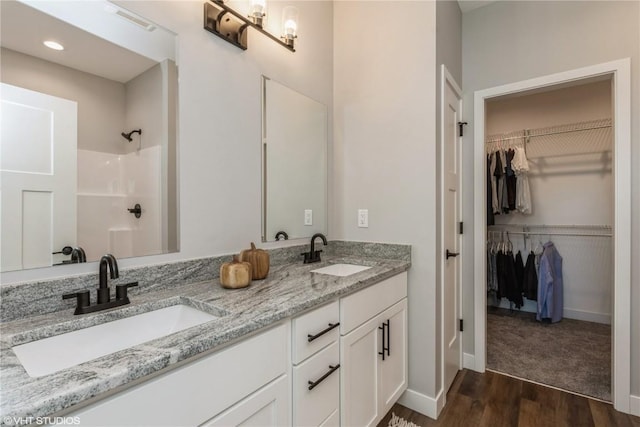 2700 Rookwood Ln, Marion, IA 52302 - bathroom featuring wood finished floors, double vanity, a shower, and a walk in closet