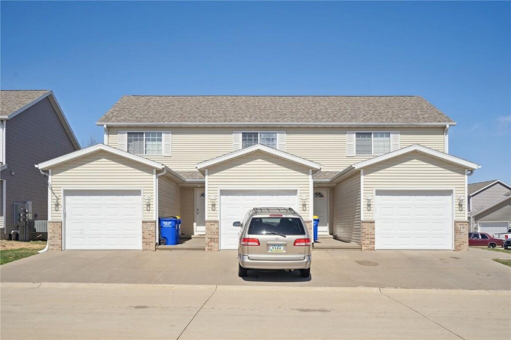 10 Alydar Dr, North Liberty, IA 52317 - view of front facade with driveway, brick siding, a garage, and roof with shingles