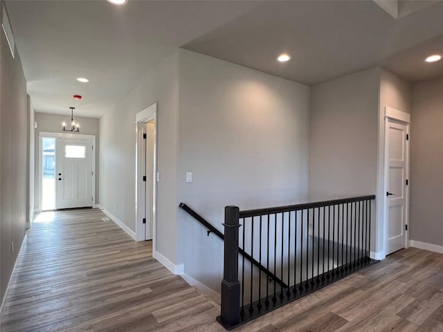 hallway with wood finished floors, an upstairs landing, recessed lighting, an inviting chandelier, and baseboards