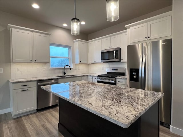 kitchen featuring light stone countertops, a sink, decorative backsplash, stainless steel appliances, and light wood-type flooring