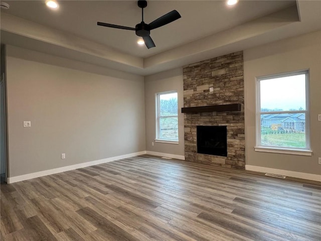 unfurnished living room featuring baseboards, visible vents, ceiling fan, wood finished floors, and a raised ceiling