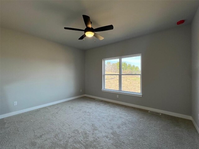 carpeted spare room with baseboards, visible vents, and a ceiling fan