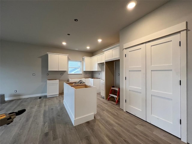 kitchen featuring recessed lighting, baseboards, a kitchen island, white cabinetry, and wood finished floors