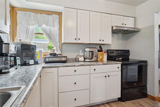 608 W 13th St, Vinton, IA 52349 - kitchen with black range with electric stovetop, under cabinet range hood, white cabinets, light wood-type flooring, and a sink