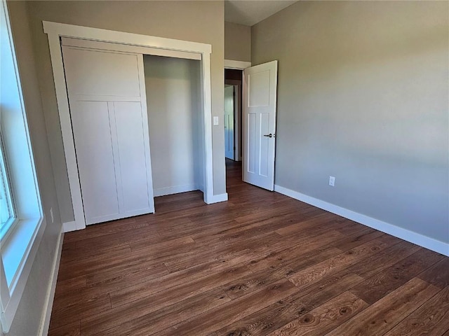 7936 217th Ave, Martelle, IA 52305 - unfurnished bedroom with dark wood-type flooring, baseboards, and a closet
