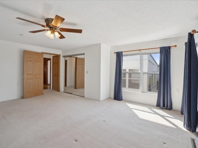 unfurnished bedroom featuring carpet floors, ceiling fan, a closet, and a textured ceiling