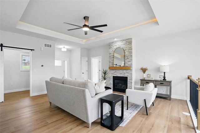 878 Silver Ln, Iowa City, IA 52245 - living area featuring a raised ceiling, a barn door, a ceiling fan, and light wood-style floors