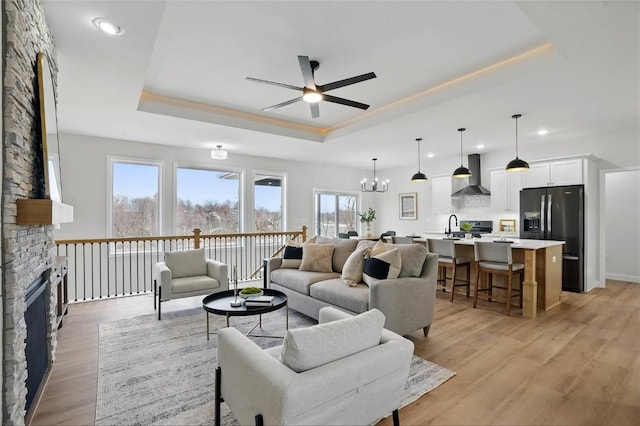 878 Silver Ln, Iowa City, IA 52245 - living area with a tray ceiling, a ceiling fan, recessed lighting, light wood-style floors, and a stone fireplace