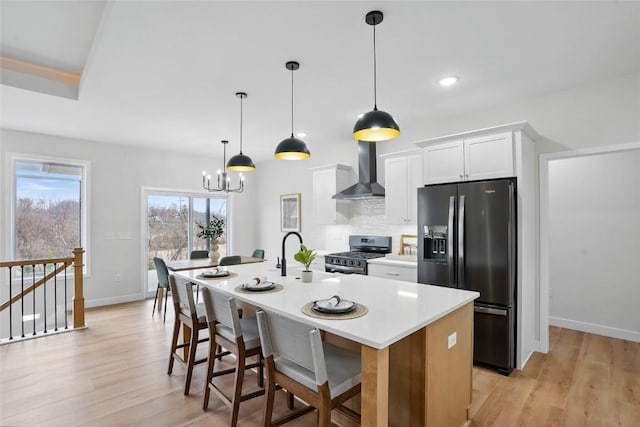 878 Silver Ln, Iowa City, IA 52245 - kitchen with refrigerator with ice dispenser, stainless steel gas range oven, wall chimney range hood, white cabinetry, and an island with sink