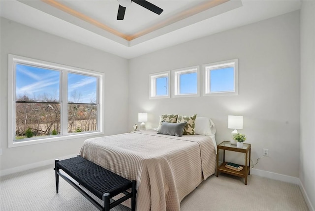 878 Silver Ln, Iowa City, IA 52245 - bedroom featuring baseboards, light carpet, a tray ceiling, and ceiling fan