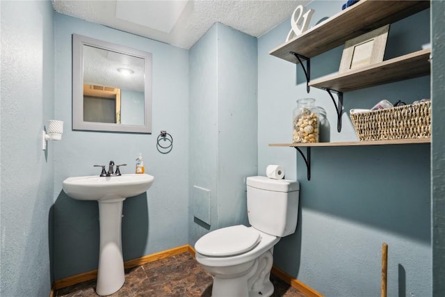 1305 W 4th St, Vinton, IA 52349 - bathroom with baseboards, a textured ceiling, toilet, and stone finish floor