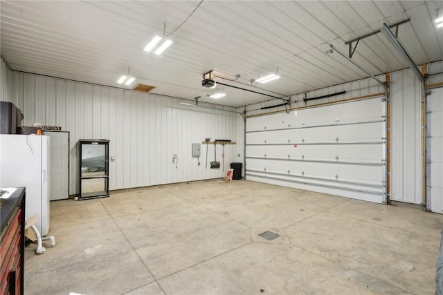 1305 W 4th St, Vinton, IA 52349 - garage featuring metal wall, a garage door opener, electric panel, and freestanding refrigerator