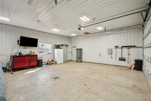 1305 W 4th St, Vinton, IA 52349 - garage featuring metal wall, a garage door opener, and a workshop area