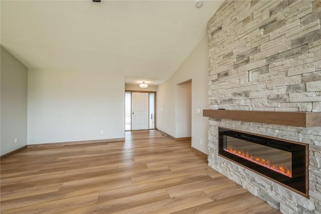 7102 Colpepper Dr SW, Cedar Rapids, IA 52404 - unfurnished living room featuring a stone fireplace, light wood-style flooring, baseboards, and lofted ceiling