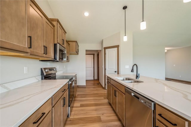 7102 Colpepper Dr SW, Cedar Rapids, IA 52404 - kitchen featuring appliances with stainless steel finishes, a sink, brown cabinetry, light wood-type flooring, and pendant lighting