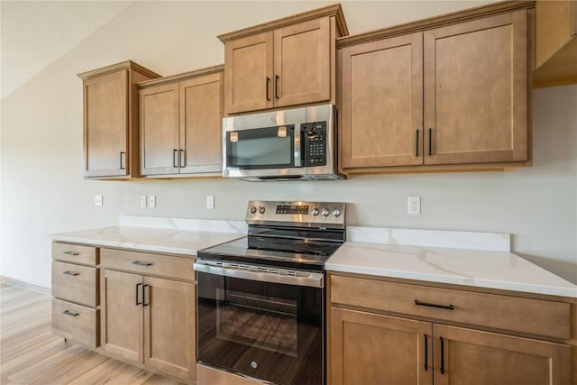 7102 Colpepper Dr SW, Cedar Rapids, IA 52404 - kitchen featuring appliances with stainless steel finishes, lofted ceiling, light wood finished floors, light stone countertops, and baseboards